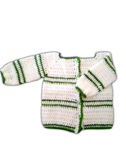 O casaco é predominantemente branco, com uma textura uniforme e delicada de crochê. As bordas, incluindo a gola, os punhos e a abertura frontal, são contornadas com um fio verde vibrante, criando um contraste harmonioso. A peça tem mangas compridas e um fecho frontal com pequenos botões. O trabalho artesanal revela a precisão dos pontos e o cuidado nos acabamentos, tornando esta peça única e especial.