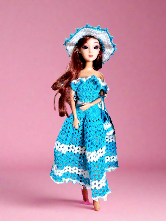 Vista frontal do vestido, maioritariamente azul, com alguns pormenores em branco como os folhos que caem a volta dos ombros e duas faixas na saia, uma a meio e outra no fundo. Tem ainda como acessórios um bonito chapéu e uma pequena bolsa ambos com a mesmas cores do vestido. 