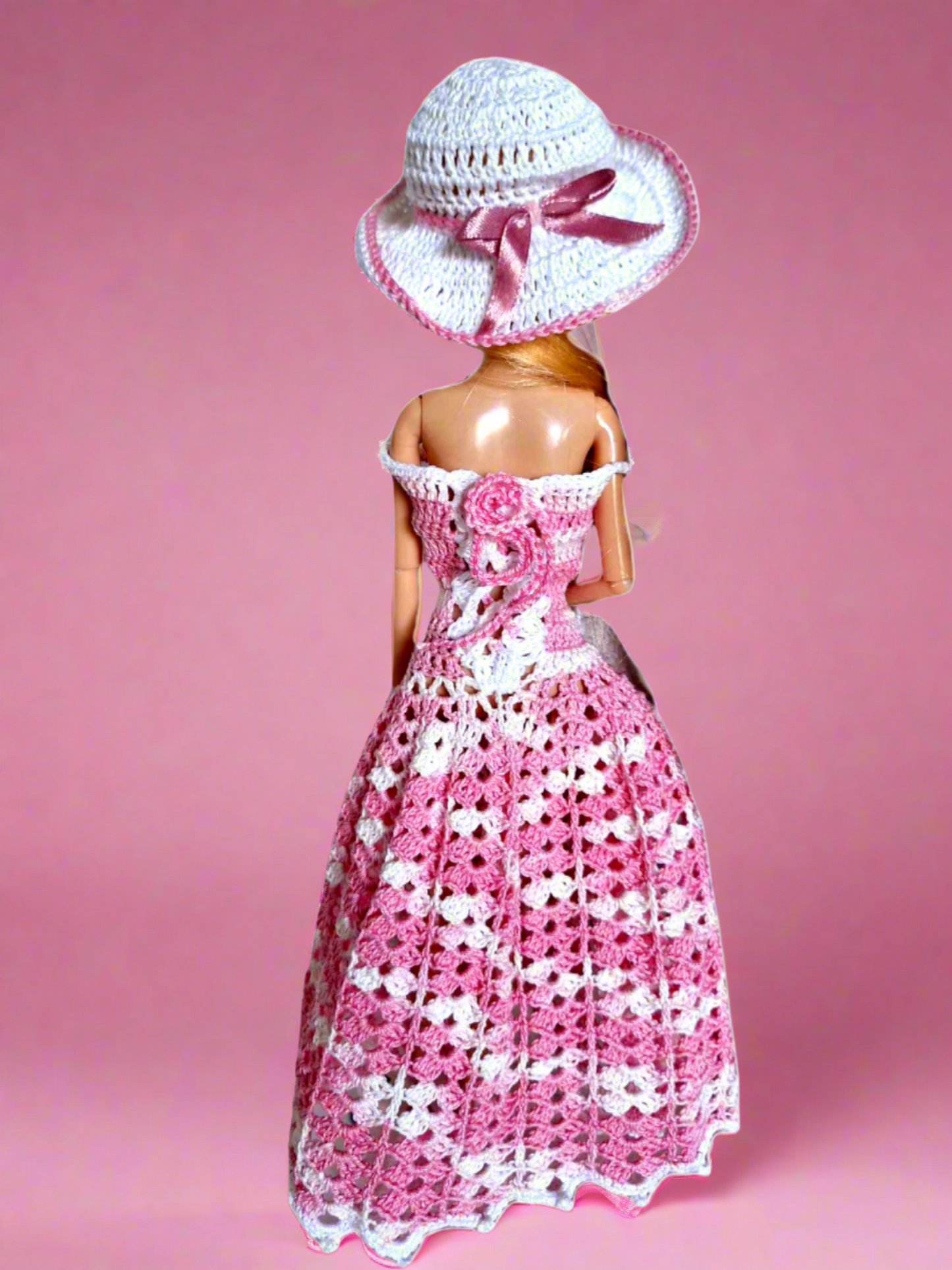 Parte de trás para dar destaque ás costas dos vestidos que é apertado como um corpete. Destaca-se ainda o elegante laço em cetim rosa no chapéu.