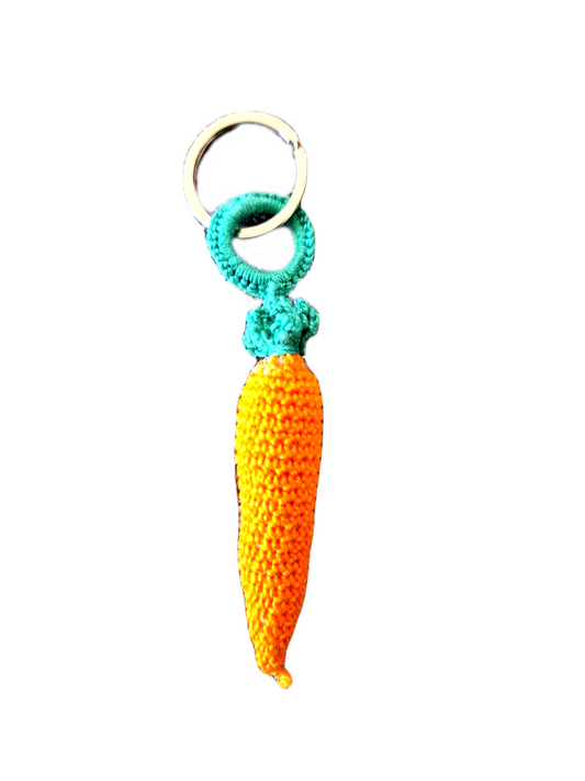 Porta Chaves com o formato de uma cenourinha bem cor de laranja, com a sua parte superior onde se encontra a argola, em verde.