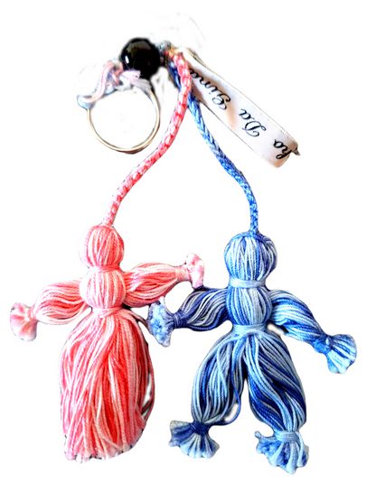 Porta Chaves com o formato de um menino e uma menina. Este é feito com  molhinhos de linhas simples, com pequenos nós para definir a forma do corpo. A menina é totalmente cor de rosa e o menino azul. 
