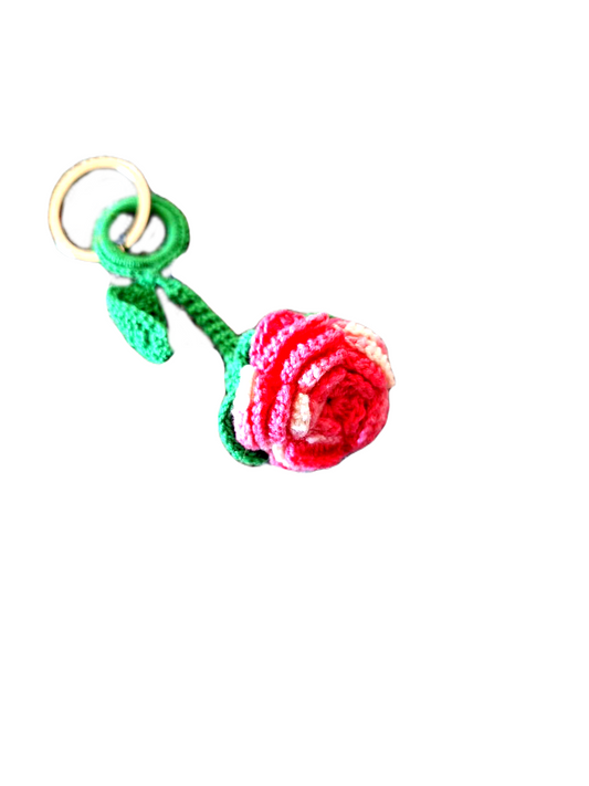 Porta chaves com o formato de uma pequena rosa, com as suas pétalas cor de rosa e o seu caule e folhas verde. 