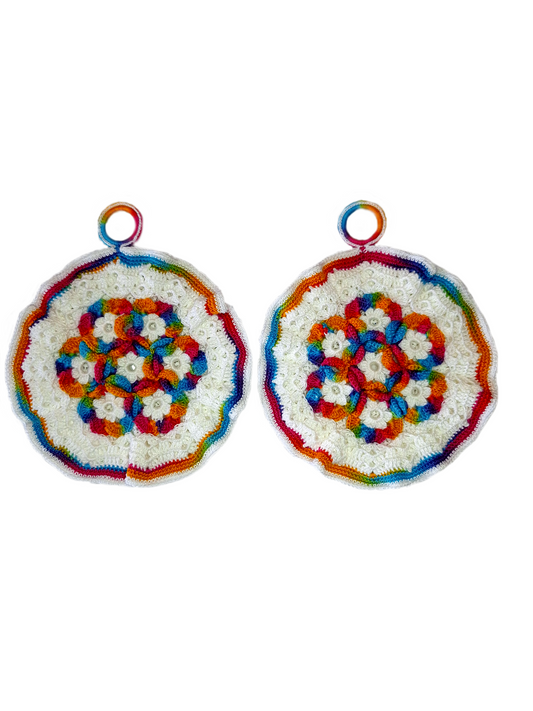 Parte frontal das pegas. Estas são redondas com rebordo em branco e matizado com as cores do arco iris. No centro tem um lindo padrão com flores brancas e o matizado a volta de cada flor.  