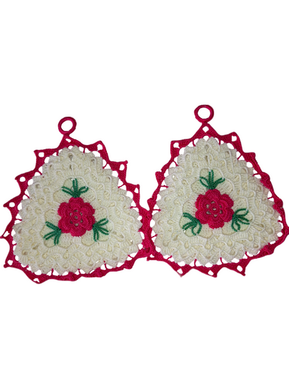 Parte frontal das pegas. Estas são triangulares, com rebordo em rosa, a base é em branco e no centro tem uma bonita flor rosa com três folhas verdes.  