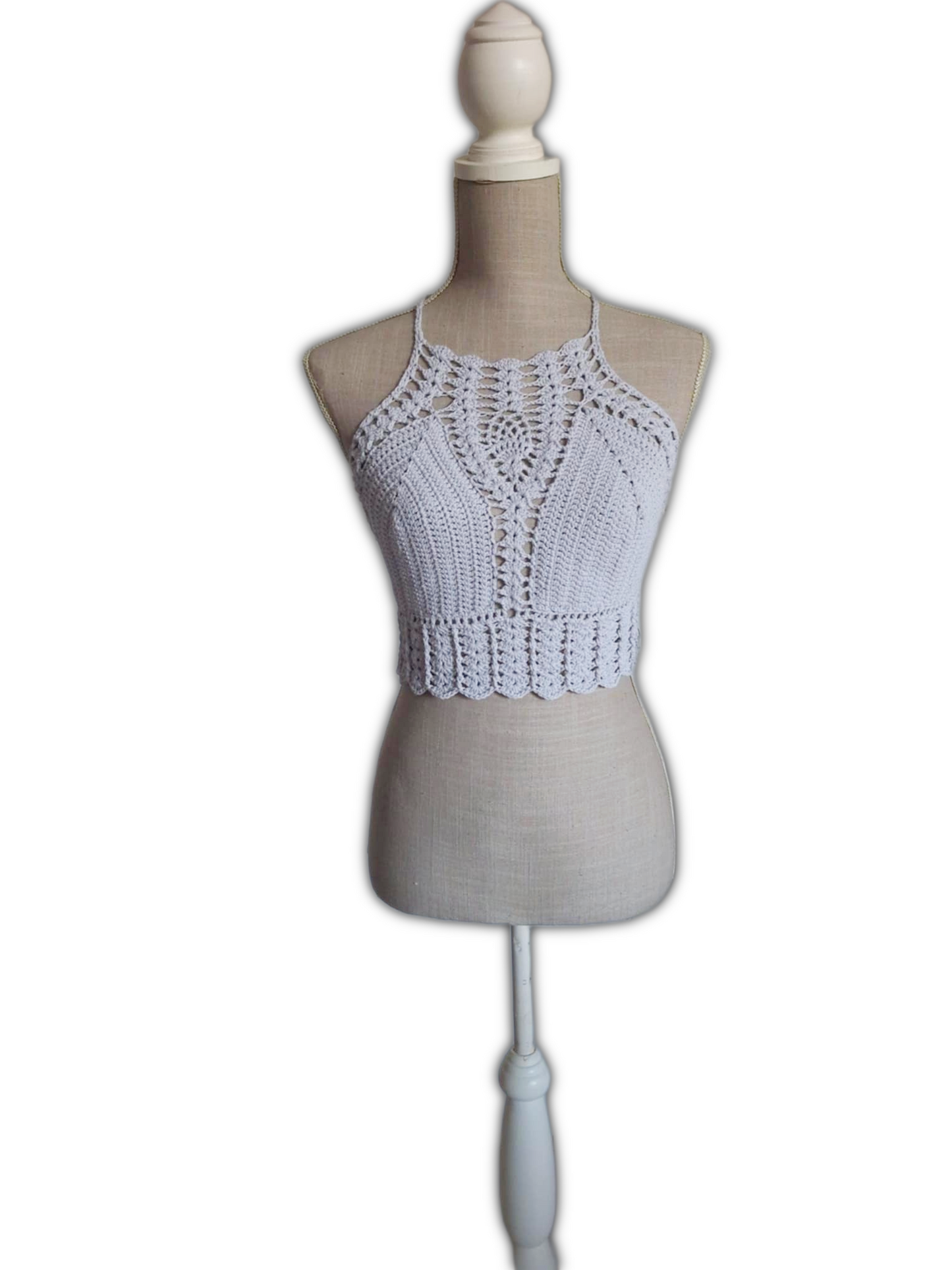 Top de crochet cinza claro sobre manequim em fundo branco. O top é estilo cropped, com alças finas e padrão rendado no centro do peito, e acabamento em ponto de conchas na parte inferior.